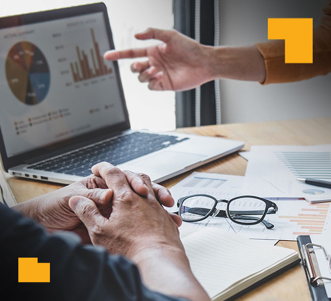 A hand points to charts and graphs on a laptop screen showing improvement